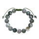 A braided bracelet featuring round beads made of tree line agate stone, with a green adjustable cord.